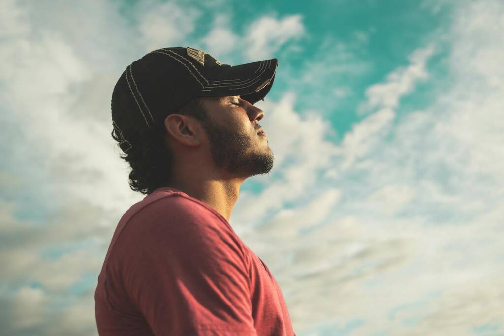 Photo by Kelvin Valerio Man Wearing Black Cap With Eyes Closed Under Cloudy Sky
